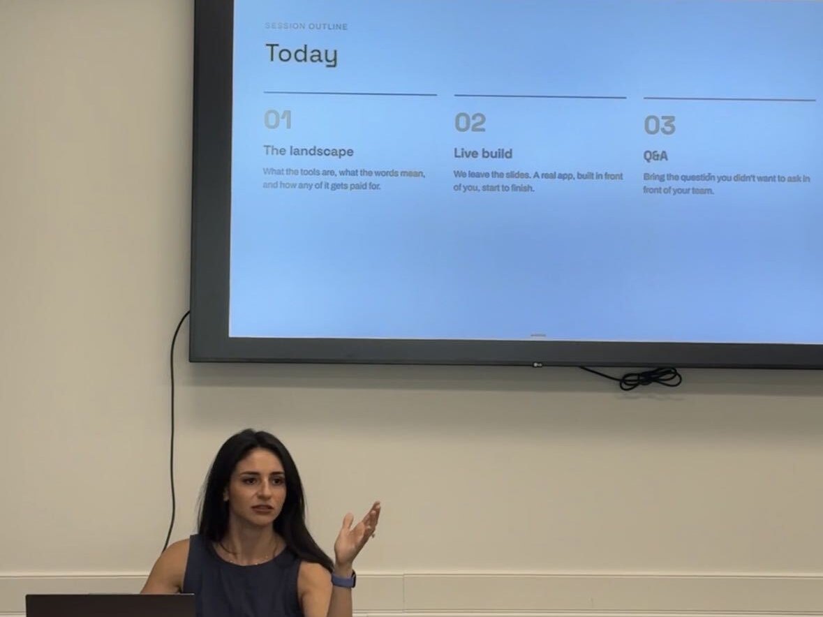 Julia at the front table with the evening's agenda on the screen behind her